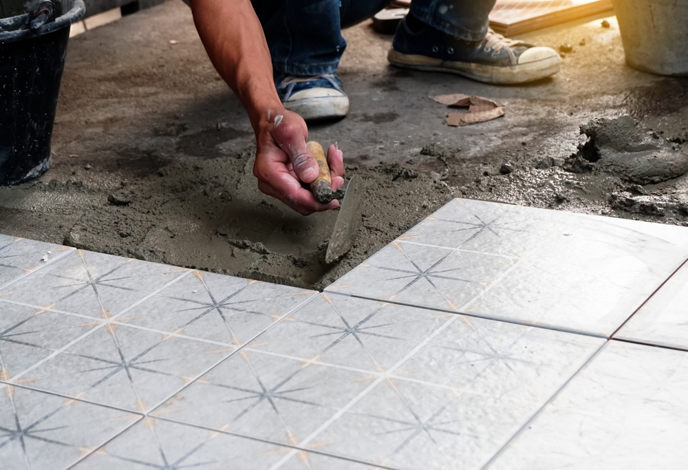 Installer spreading mortar beside patterned floor tile