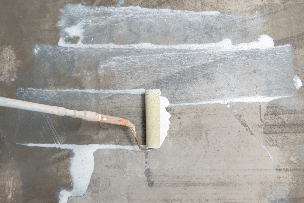 Roller applying a coating to a concrete floor