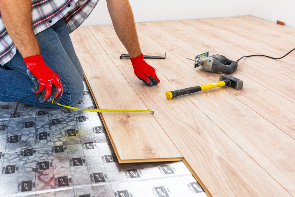 Installer measuring a plank over flooring underlayment