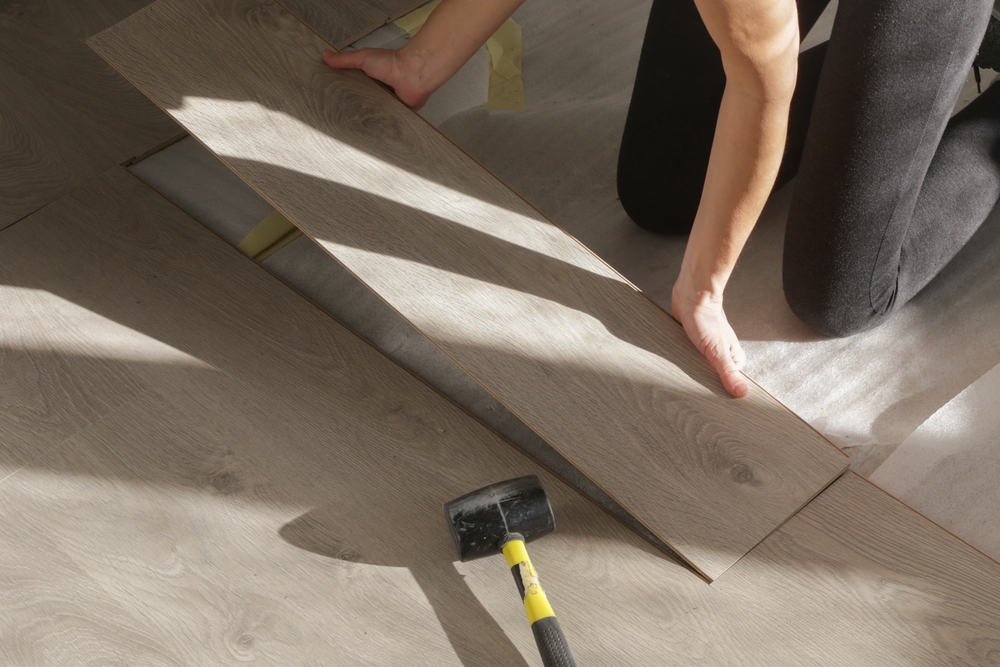Installer fitting a light-colored floor plank