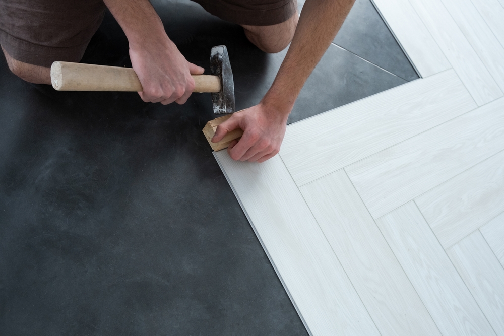 Installer tapping a floor plank into place